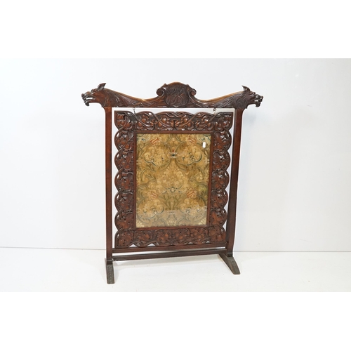 684 - Victorian mahogany framed fire screen, having carved top rail dated 1889 flanked with dogs mask head... 