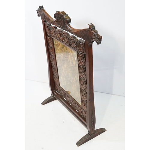 684 - Victorian mahogany framed fire screen, having carved top rail dated 1889 flanked with dogs mask head... 