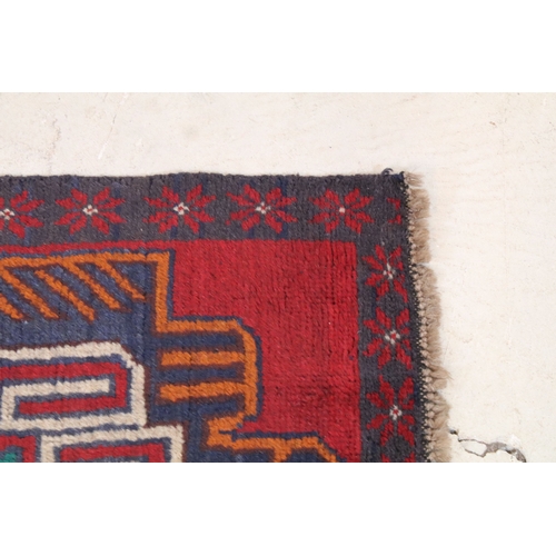589 - Baluchi rug having a red ground with two geometric medallions to the central panel, 152cm x 88cm