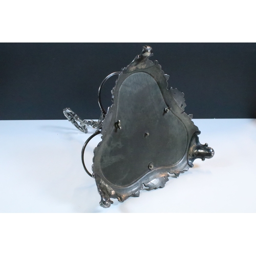 148 - Early 20th century silver plated bottle holder / decanter with ornate handle raised on scroll feet, ... 