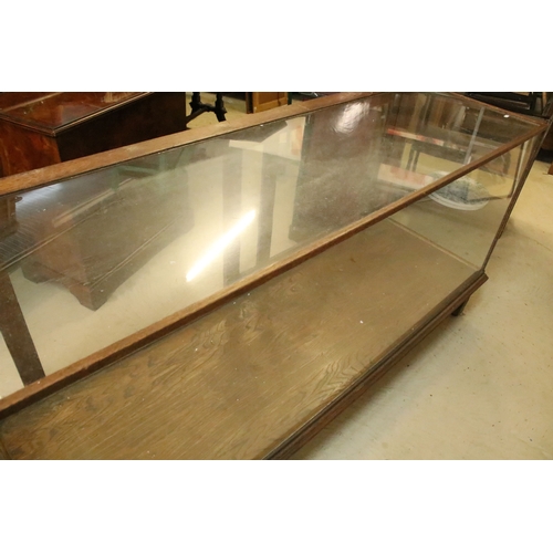 555 - Early 20th century oak and glass display case, having vacant interior with sliding doors to rear, ra... 
