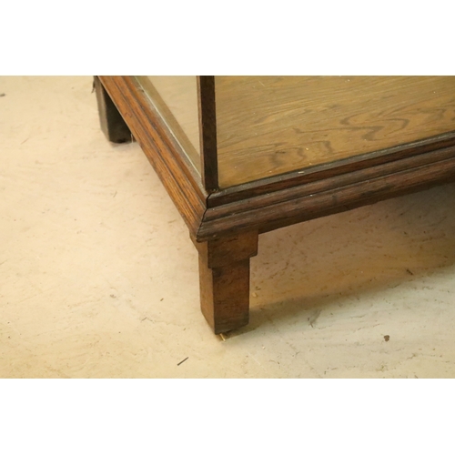 555 - Early 20th century oak and glass display case, having vacant interior with sliding doors to rear, ra... 