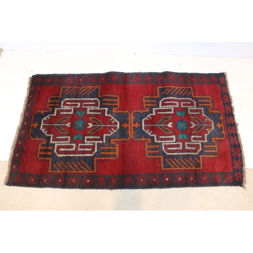 589 - Baluchi rug having a red ground with two geometric medallions to the central panel, 152cm x 88cm