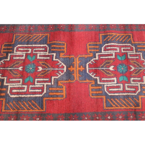 589 - Baluchi rug having a red ground with two geometric medallions to the central panel, 152cm x 88cm