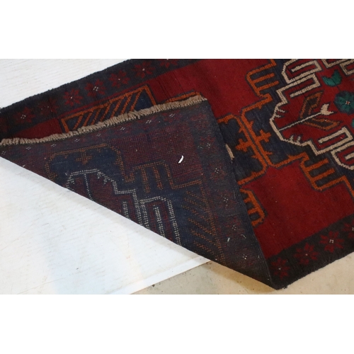 589 - Baluchi rug having a red ground with two geometric medallions to the central panel, 152cm x 88cm
