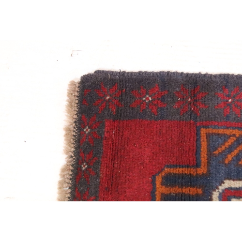 589 - Baluchi rug having a red ground with two geometric medallions to the central panel, 152cm x 88cm