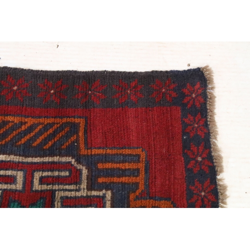 589 - Baluchi rug having a red ground with two geometric medallions to the central panel, 152cm x 88cm