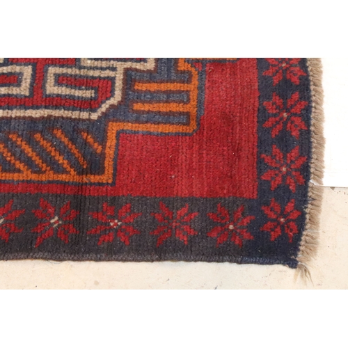 589 - Baluchi rug having a red ground with two geometric medallions to the central panel, 152cm x 88cm