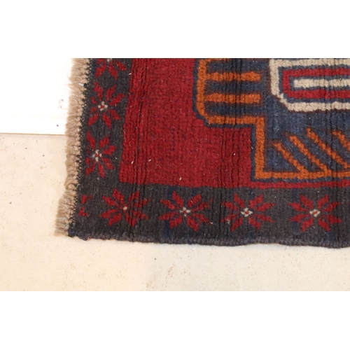 589 - Baluchi rug having a red ground with two geometric medallions to the central panel, 152cm x 88cm