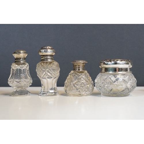 333 - A collection of vanity jars and bottles to include silver topped examples.