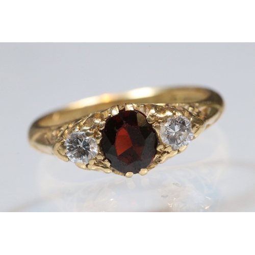 36 - 18ct gold, garnet and diamond three stone ring. The ring being set with a round cut red garnet to ce... 