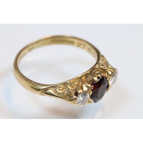 36 - 18ct gold, garnet and diamond three stone ring. The ring being set with a round cut red garnet to ce... 