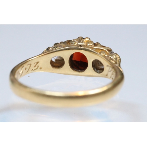 36 - 18ct gold, garnet and diamond three stone ring. The ring being set with a round cut red garnet to ce... 