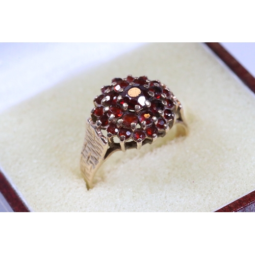 195 - 9ct gold and garnet cluster ring. The ring having a round head set with round cut garnets with textu... 