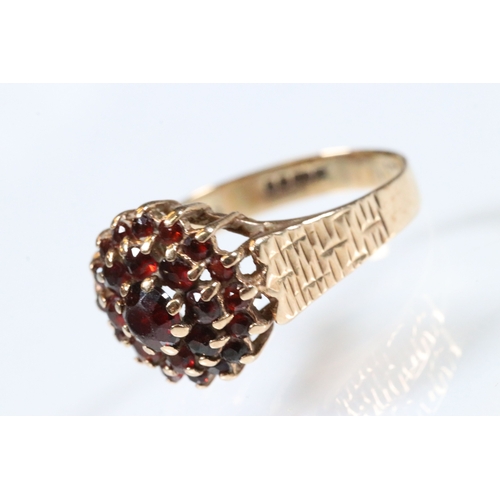195 - 9ct gold and garnet cluster ring. The ring having a round head set with round cut garnets with textu... 