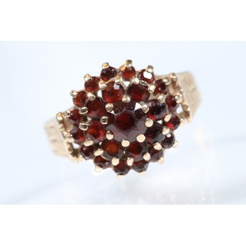 195 - 9ct gold and garnet cluster ring. The ring having a round head set with round cut garnets with textu... 