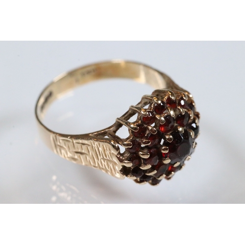 195 - 9ct gold and garnet cluster ring. The ring having a round head set with round cut garnets with textu... 