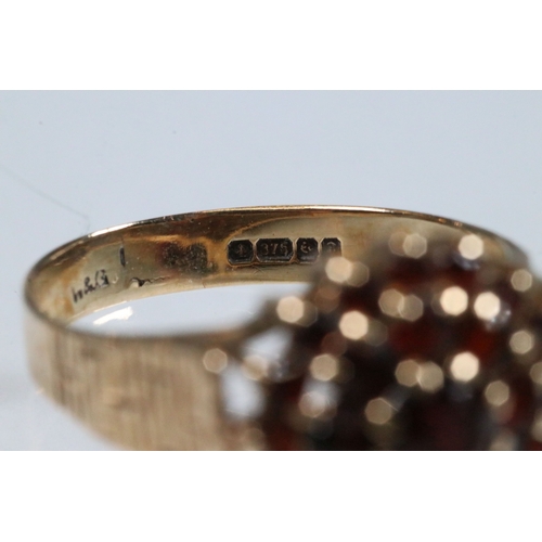 195 - 9ct gold and garnet cluster ring. The ring having a round head set with round cut garnets with textu... 