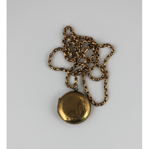 343 - A gold back and front circular pendant locket with engraved decoration, with a gold faceted oval lin... 