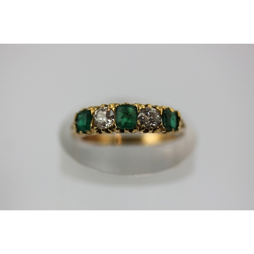 494 - A gold emerald and diamond five stone ring mounted with three rectangular cut emeralds and with two ... 