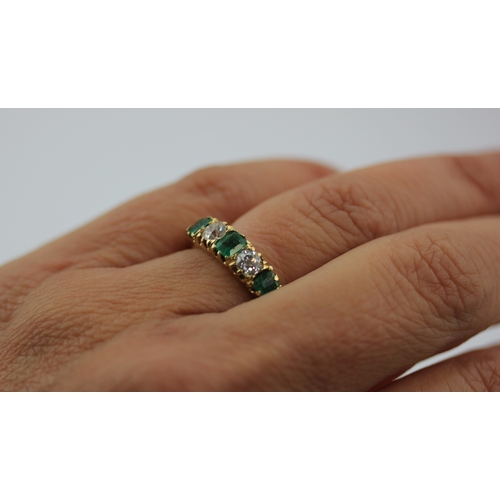 494 - A gold emerald and diamond five stone ring mounted with three rectangular cut emeralds and with two ... 