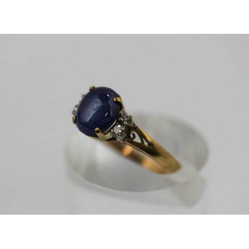 495 - A gold sapphire and diamond ring claw set with a cabochon sapphire at the centre between two pairs o... 