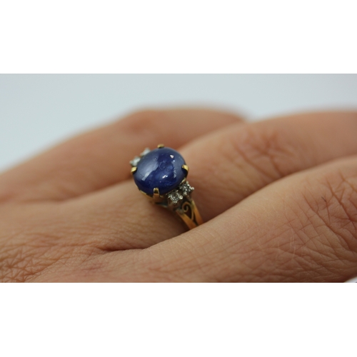 495 - A gold sapphire and diamond ring claw set with a cabochon sapphire at the centre between two pairs o... 