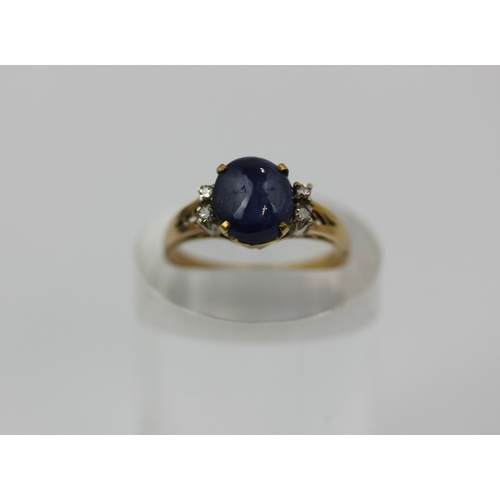 495 - A gold sapphire and diamond ring claw set with a cabochon sapphire at the centre between two pairs o... 