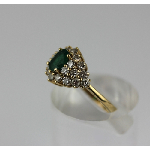 501 - A gold emerald and diamond cluster ring claw set with the oval cut emerald within a surround of circ... 