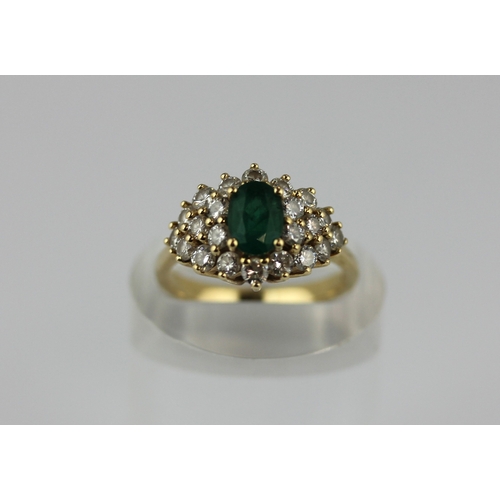 501 - A gold emerald and diamond cluster ring claw set with the oval cut emerald within a surround of circ... 