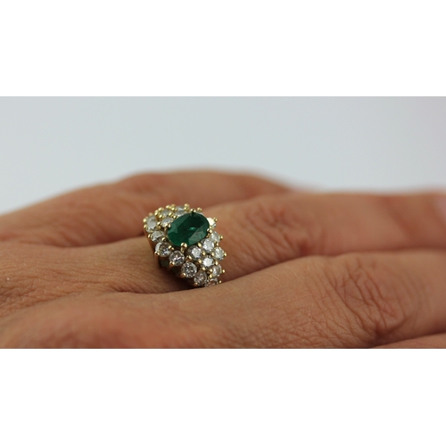 501 - A gold emerald and diamond cluster ring claw set with the oval cut emerald within a surround of circ... 