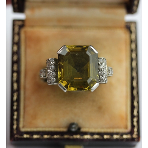 503 - A diamond and olive coloured gemstone ring in an Art Deco design, unmarked, ring size Q 1/2, 10g, in... 