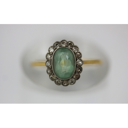 505 - A gold diamond and pale green gemstone oval cluster ring, collet set with the oval cut pale green ge... 