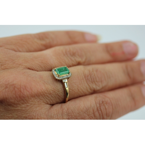 507 - A 9ct gold emerald and diamond rectangular cluster ring claw set with the rectangular cut emerald wi... 