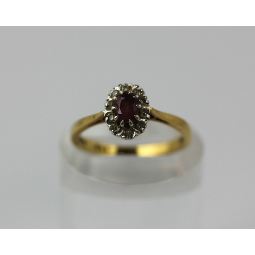 512 - An 18ct gold ruby and diamond oval cluster ring claw set with the oval cut ruby in a surround of cir... 