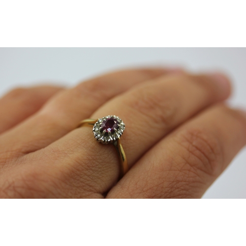 512 - An 18ct gold ruby and diamond oval cluster ring claw set with the oval cut ruby in a surround of cir... 