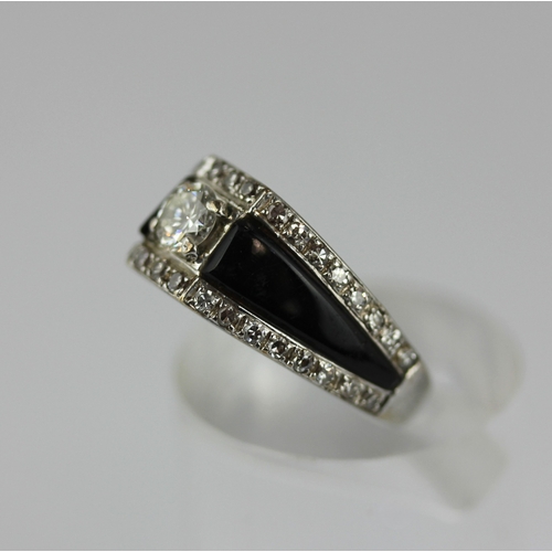 516 - A diamond and black onyx ring claw set with the principal circular cut diamond between black onyx sh... 