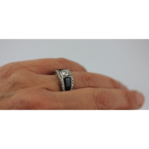 516 - A diamond and black onyx ring claw set with the principal circular cut diamond between black onyx sh... 