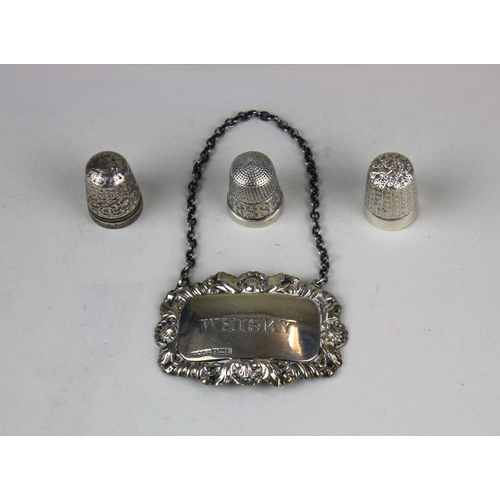 64 - An Elizabeth II silver decanter label for 'Whisky' and two silver thimbles, combined gross weight 0.... 