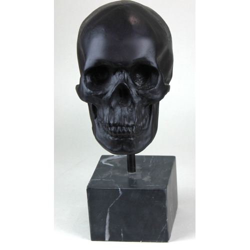 179 - A heavy quality skull sculpture, solid brass in a bronze finish mounted on a black marble base, 37cm... 