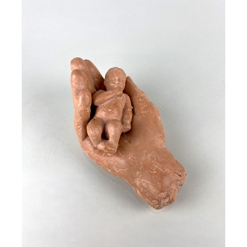 35 - Susan Hadley, a terracotta model of a child resting in a hand, paper label verso 21cm long... 