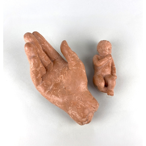 35 - Susan Hadley, a terracotta model of a child resting in a hand, paper label verso 21cm long... 