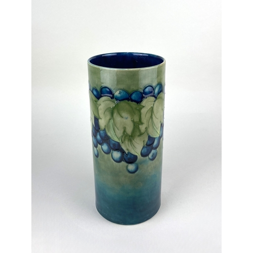 43 - A William Moorcroft 'leaf and berry' pattern vase of cylinder form, decorated in blue and green 25cm... 