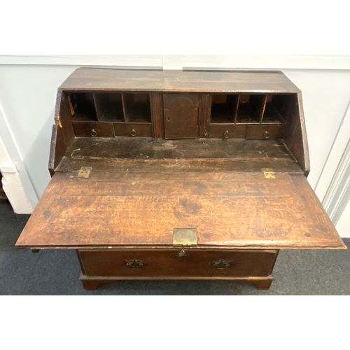 474 - A George III oak bureau with fall enclosing pigeon holes and small drawers, over two short and three... 