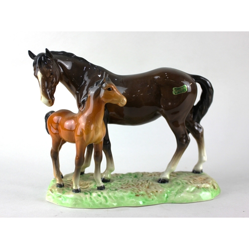 79 - A Beswick model horse group depicting brown horse and foal on shaped oval green base 19cm high... 