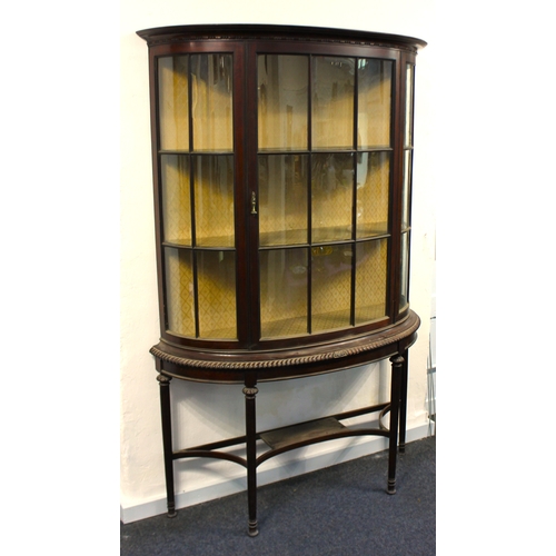 573 - An early 20th century mahogany demi-lune display cabinet with central glazed door, enclosing three s... 