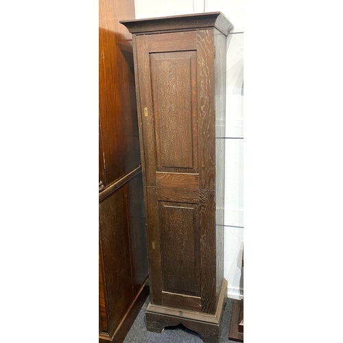 594 - An Edwardian oak tall narrow side cabinet in a Georgian taste, having two fielded panelled cupboard ... 