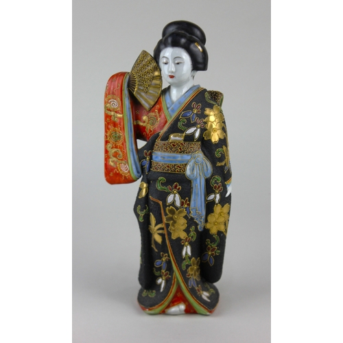 494 - A Japanese Satsuma porcelain model of a female figure, wearing traditional robes and holding a fan, ... 