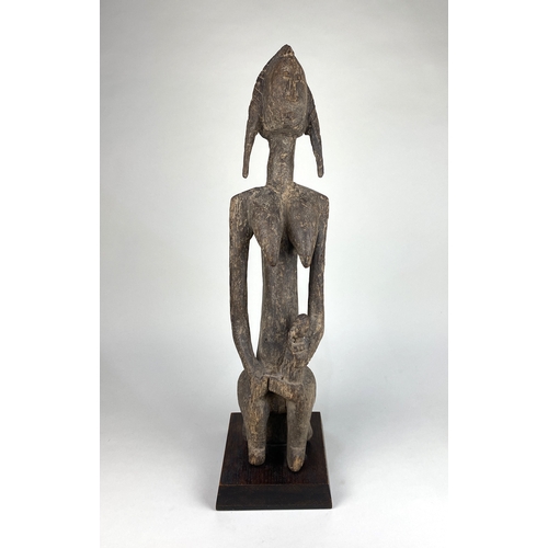 129 - An African carved wood Bambara maternity figure, Mali, probably late 19th / early 20th century, the ... 