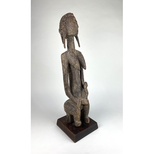 129 - An African carved wood Bambara maternity figure, Mali, probably late 19th / early 20th century, the ... 